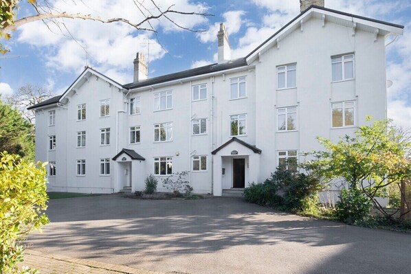 A white two-story building with a central entrance, multiple windows, and a driveway.