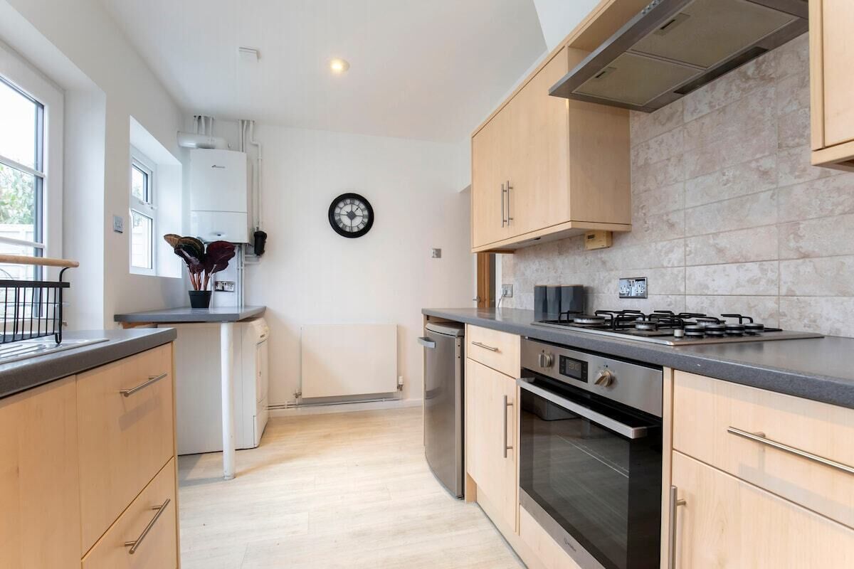 A modern kitchen with light wood cabinets, a gas stove, and a dishwasher.