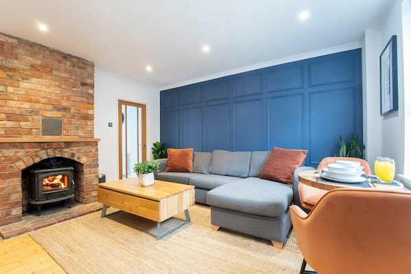 A cozy living room with a brick fireplace, a grey sofa, and a wooden coffee table.