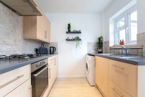 A modern kitchen with a gas stove, oven, dishwasher, and a window with a view.