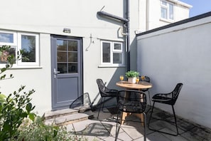 A patio with a table and chairs, a door, and a small window.