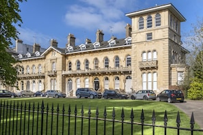 A row of terraced houses with a well-maintained lawn and a black metal fence in the foreground.