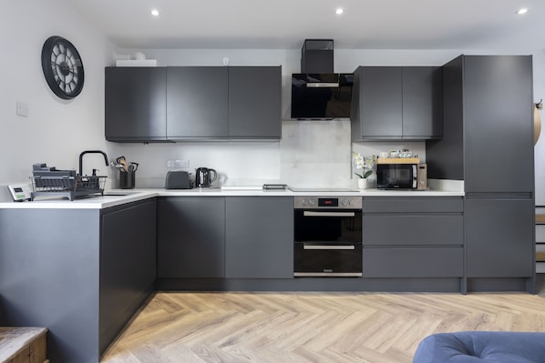 A modern kitchen with grey cabinets, a built-in oven, and a microwave.