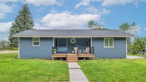 A single-story house with a front porch, a small garden, and a clear sky.