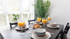 A breakfast table set with plates, bowls, glasses of orange juice, and pastries. - Modern Two Bedroom Two Bathroom Home (Gloucestershire)