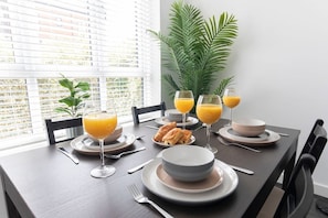 A breakfast table set with plates, bowls, glasses of orange juice, and pastries.