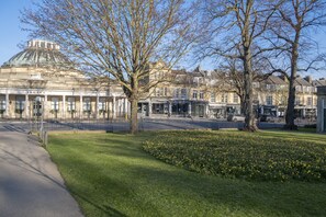 Een historisch gebouw met een grote koepel en klassieke architectuur, omringd door een fraai onderhouden gazon en bomen.