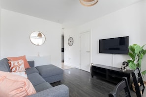 Una sala de estar moderna con un sofá seccional gris, un mueble de entretenimiento negro y un televisor de pantalla plana.