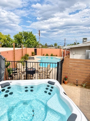 Un jardin avec une piscine, un jacuzzi et du mobilier d’extérieur.