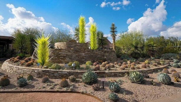 A desert garden with various cacti and succulents, a stone wall, and a clear blue sky. - Tempe Getaway w/Pool & Near ASU! (Tempe)