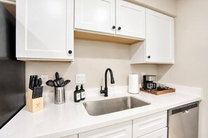 Una cucina moderna con mobili bianchi, un lavello in acciaio inossidabile e una macchina da caffè.
