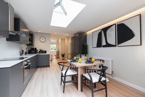 A modern kitchen with a skylight, a dining area with a table set for four, and a large window.