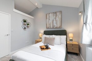 A modern bedroom with a bed, bedside tables, a geometric wall decoration, and a painting.