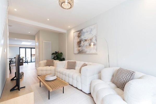 A modern living room with a white sofa, a wooden coffee table, and a floor lamp.