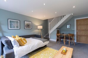 A bedroom with a bed, bedside table, lamp, and a dining area with a table and chairs.