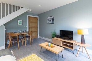 Un salon comprenant un coin repas, un escalier, un téléviseur et une lampe.