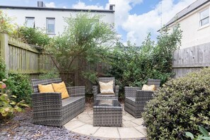 A patio area with wicker furniture, including a sofa and two armchairs, and a small table.