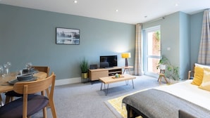 A modern living room with a dining area, a bed, and a TV. - Peaceful & Spacious 2 Bed Home in Cheltenham (Gloucestershire)