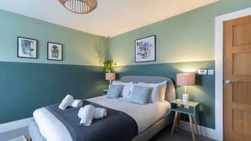 A bedroom with a bed, bedside tables, a door, and wall art.