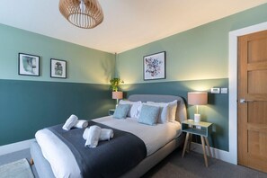 A bedroom with a bed, bedside tables, a door, and wall art.