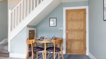 A dining area with a wooden table and chairs, a staircase, and a wooden door.