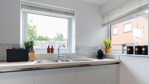 A modern kitchen with a large window, a sink, and a coffee machine. - Peaceful & Spacious 2 Bed Home in Cheltenham (Gloucestershire)