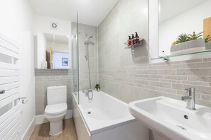 A modern bathroom with a toilet, a bathtub, and a sink.