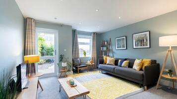 A modern living room with a sofa, a coffee table, a lamp, and a bookshelf.