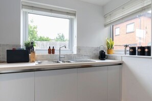 A modern kitchen with a large window, a sink, and a coffee machine. - Quiet Twin Homes: 5 Beds, 3 Baths & Parking For 3 (Gloucestershire)