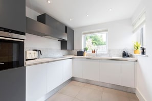 Una cocina moderna con armarios blancos, horno empotrado y ventana que proporciona luz natural.