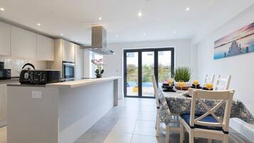 A modern kitchen with white cabinetry, a central island, and a dining area with a table set for four.