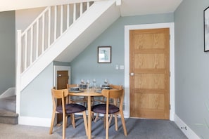 Un coin repas avec une table et des chaises en bois, un escalier et une porte en bois.