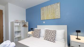 A bedroom with a bed, two bedside tables, a wardrobe, and a wall-mounted artwork.