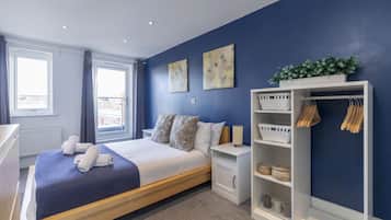 Un dormitorio moderno con cama, mesitas de noche, un armario y una ventana.