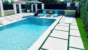 Una piscina rectangular amb un solàrium enrajolat, envoltada per una paret baixa i un altell.