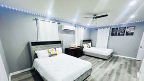 Un dormitori amb dos llits, un aparell d'aire condicionat, un ventilador de sostre i llums LED al sostre.