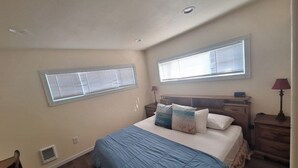 Een slaapkamer met een bed, twee nachtkastjes, een raam en een lamp.