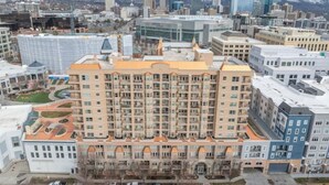 A multi-story hotel with a central courtyard, surrounded by other buildings.