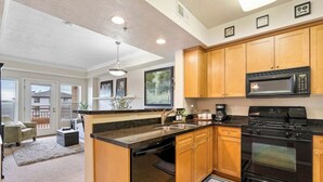 A modern kitchen with wooden cabinets, a black stove, and a microwave.