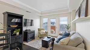 A living room with a sofa, coffee table, and a bookshelf. There is a door leading to a balcony.