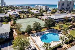 Zona residencial con cancha de tenis, piscina y vista a la playa.
