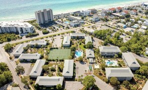 Vista aérea de un resort con varias edificaciones, una cancha de tenis y una zona de piscina.