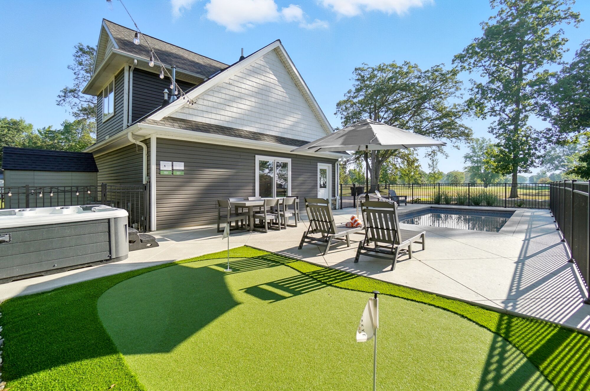 A house with a patio, outdoor seating, a hot tub, and a swimming pool.