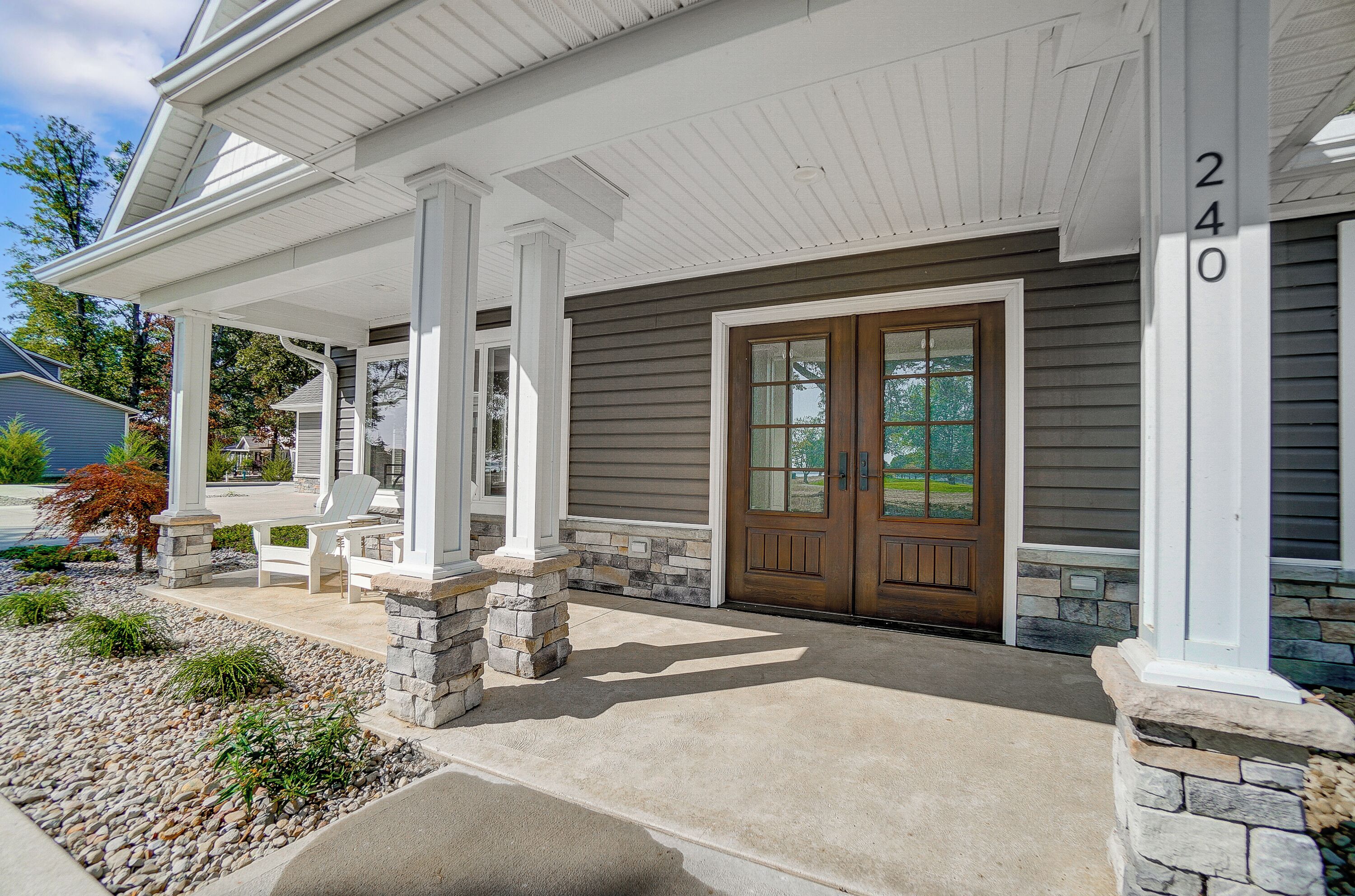 A house with a covered porch, stone pillars, and a double door.