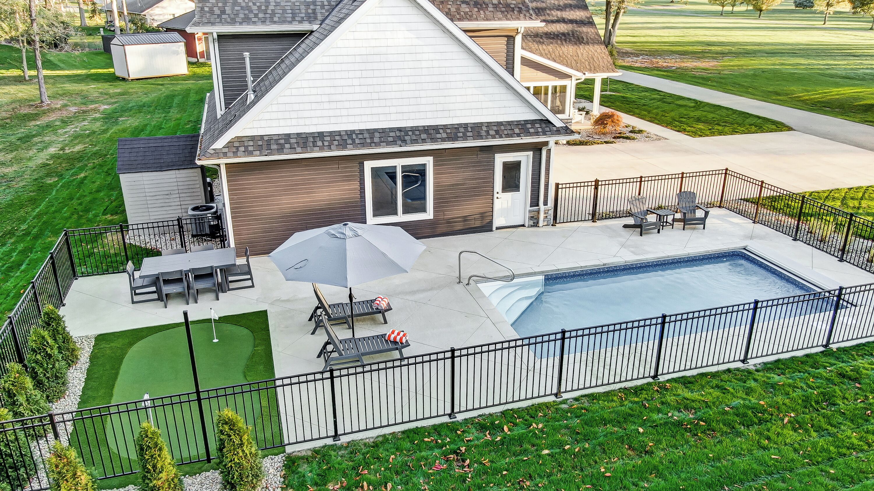 Une propriété résidentielle dotée d’une piscine, de mobilier de jardin et d’une cour clôturée.