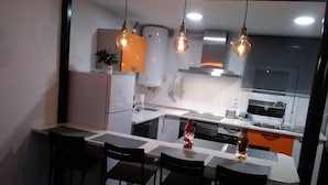 A modern kitchen with a central island, bar stools, pendant lighting, and a view into the adjacent dining area. - Encanto Cuenca - Weather Bridge (Cuenca)