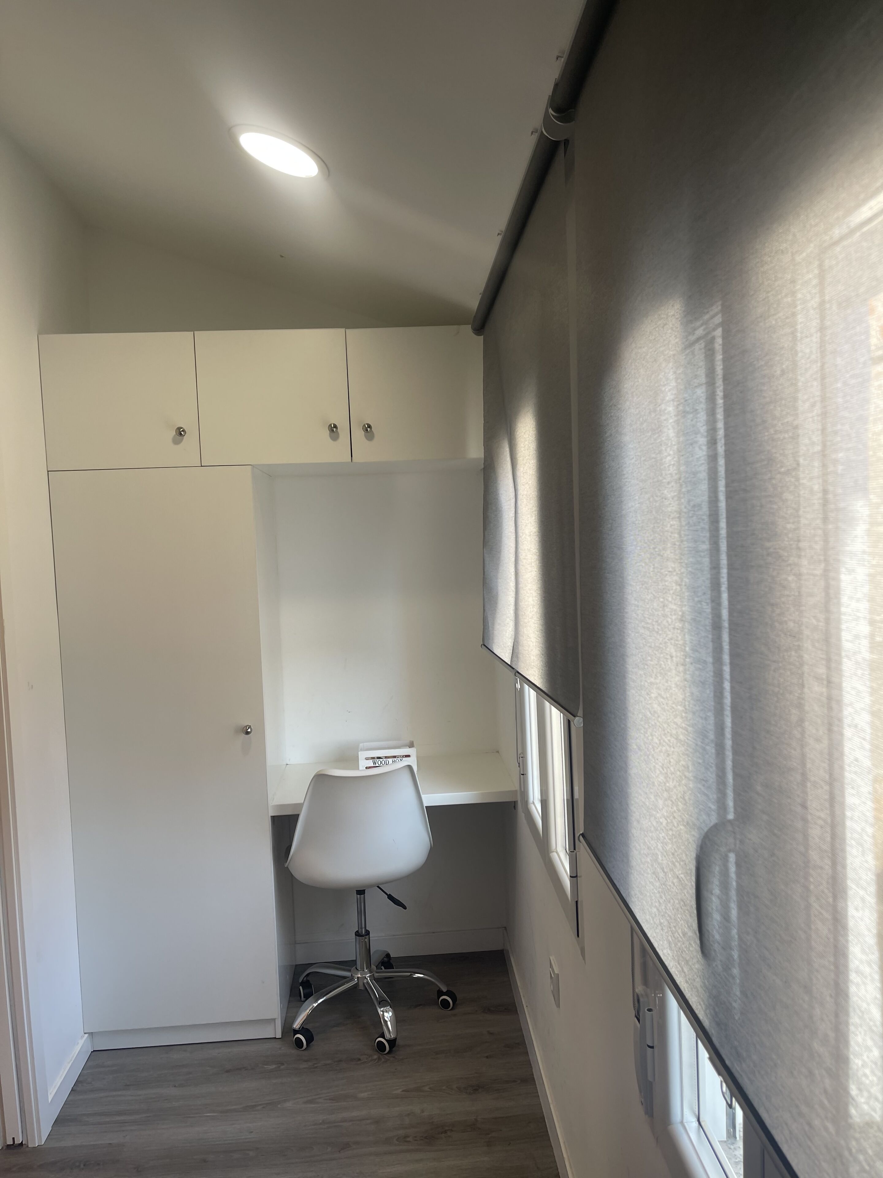 A small office space with a white desk, a chair, and a white wardrobe.