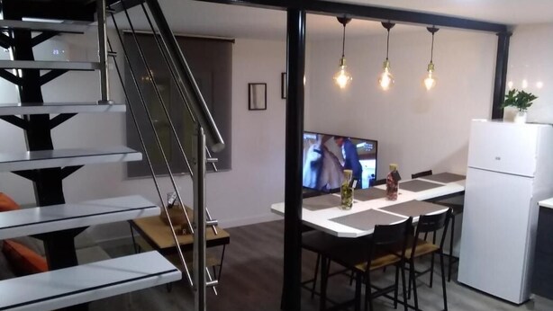 A modern kitchen with a dining area, a staircase, and a flat-screen TV. - Encanto Cuenca - Weather Bridge (Cuenca)