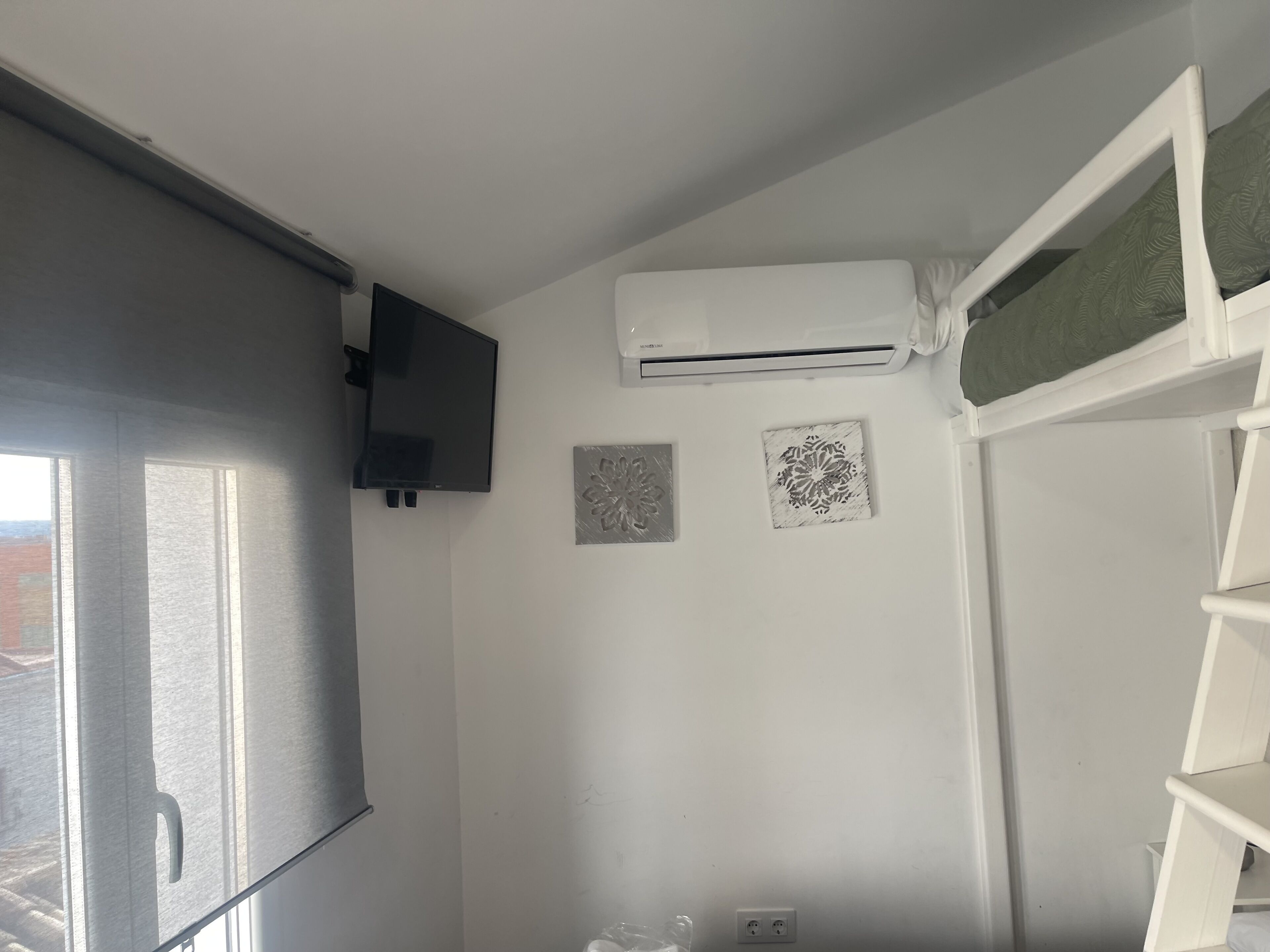Una habitación con un ventanal grande, un equipo de aire acondicionado y dos paneles decorativos en la pared.