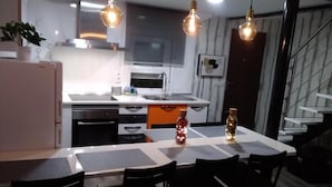 A modern kitchen with a dining area, featuring pendant lights, a refrigerator, and a staircase. - Encanto Cuenca - Weather Bridge (Cuenca)